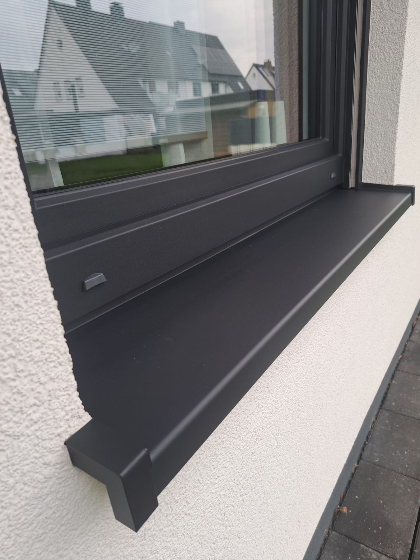 Nahaufnahme eines dunkelgrauen Fensterprofils und der Fensterbank